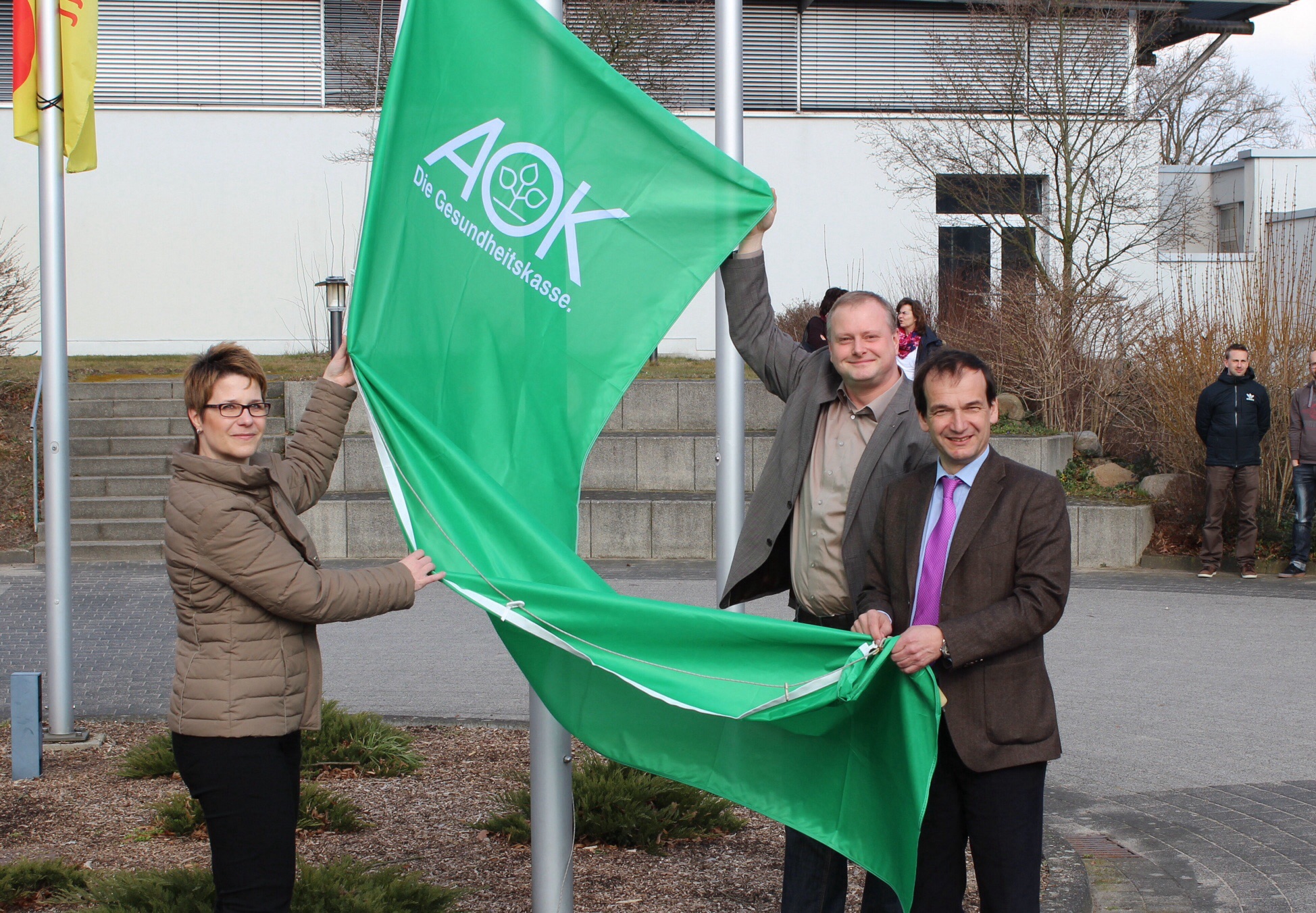 Sportschulleiterin Stefanie Lück, Henry Saage (Landesrepräsentant der AOK Sachsen-Anhalt) und LSB-Präsident Andreas Silbersack beim Hissen der AOK-Fahne in Osterburg.
